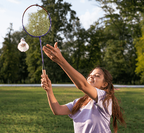 Young woman playing badminton outdoors